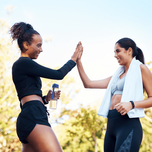 Two women high-fiving in workout gear.